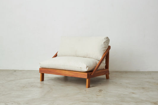 Poltrona Amyr de madeira com futons claros sobre fundo neutro