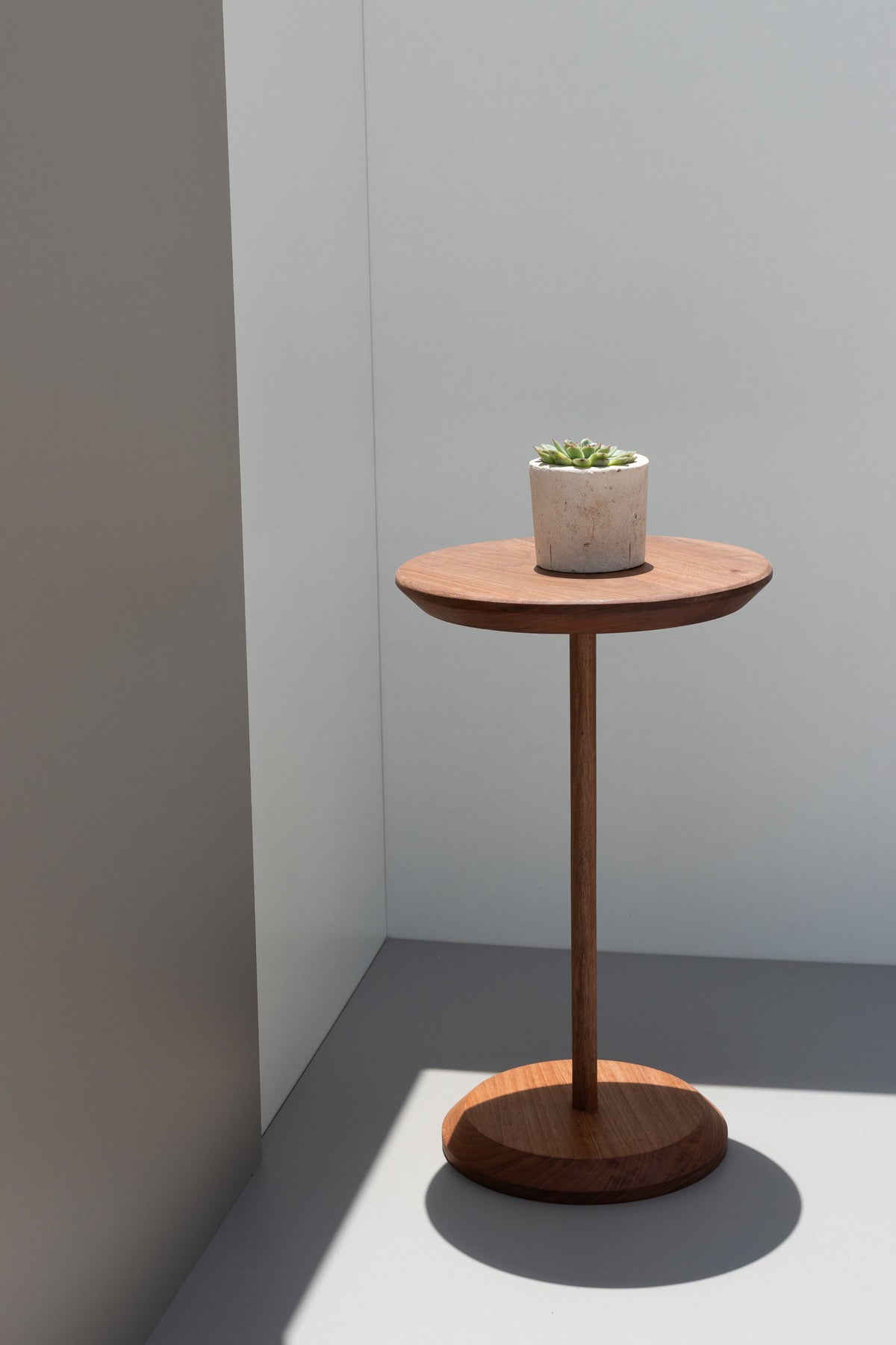 Mesa lateral Serena em ambiente iluminado pelo sol, com pequeno vaso sobre o tampo.