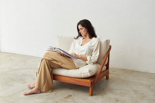 Pessoa lendo sentada na Poltrona Amyr com futons claros